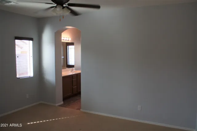 an empty room with a chandelier fan and windows