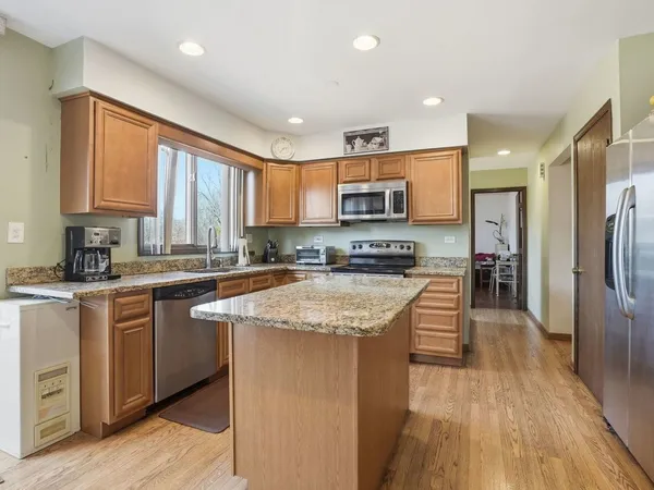 a kitchen with stainless steel appliances granite countertop a stove a sink a refrigerator a center island and a window