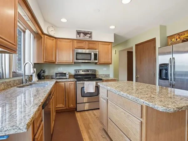 a kitchen with stainless steel appliances granite countertop a sink stove microwave and refrigerator