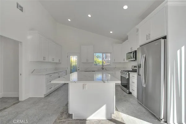 a kitchen with white cabinets and refrigerator