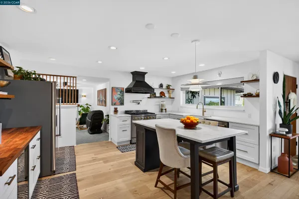 a kitchen with stainless steel appliances granite countertop a table chairs and a refrigerator