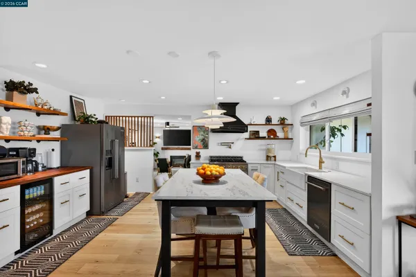 a kitchen with stainless steel appliances granite countertop a stove a sink dishwasher a dining table and chairs with wooden floor