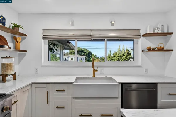 a kitchen with granite countertop a stove a sink a refrigerator and cabinets