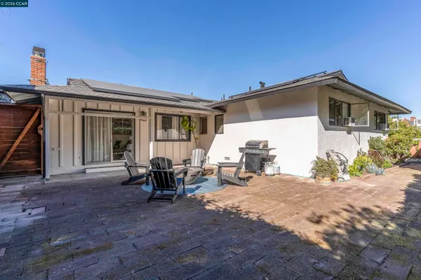a view of a patio with table and chairs potted plants and a large tree