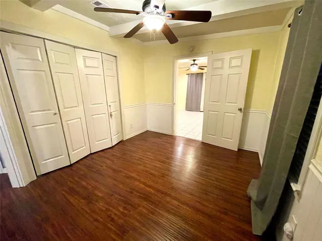 an empty room with wooden floor and fan