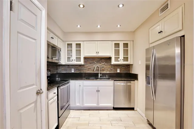 a kitchen with granite countertop white cabinets and black appliances