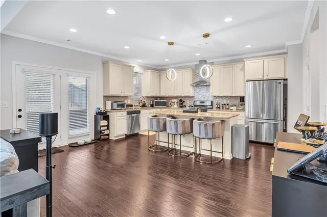 a kitchen with stainless steel appliances kitchen island granite countertop wooden floors and white cabinets