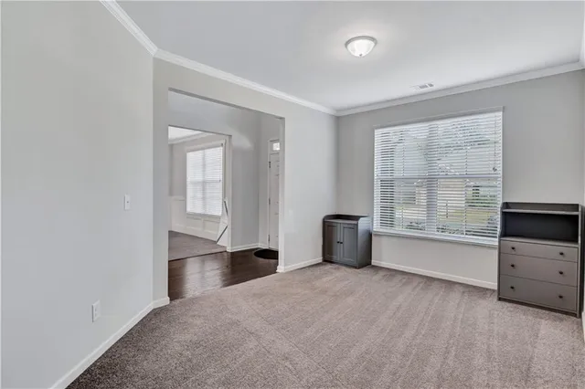 a view of an empty room with a window and a kitchen