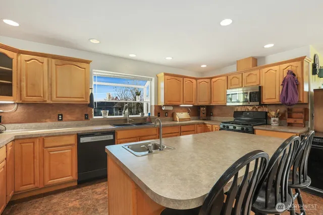 a kitchen with stainless steel appliances granite countertop a stove a refrigerator a kitchen island a stove and a refrigerator