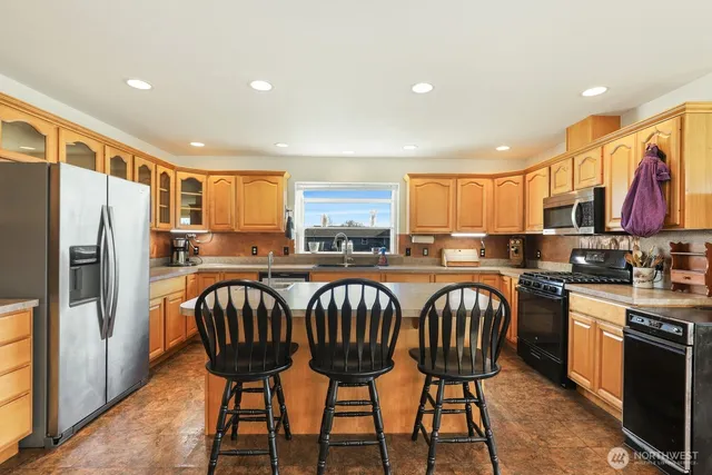 a kitchen with stainless steel appliances granite countertop a sink a stove and a refrigerator