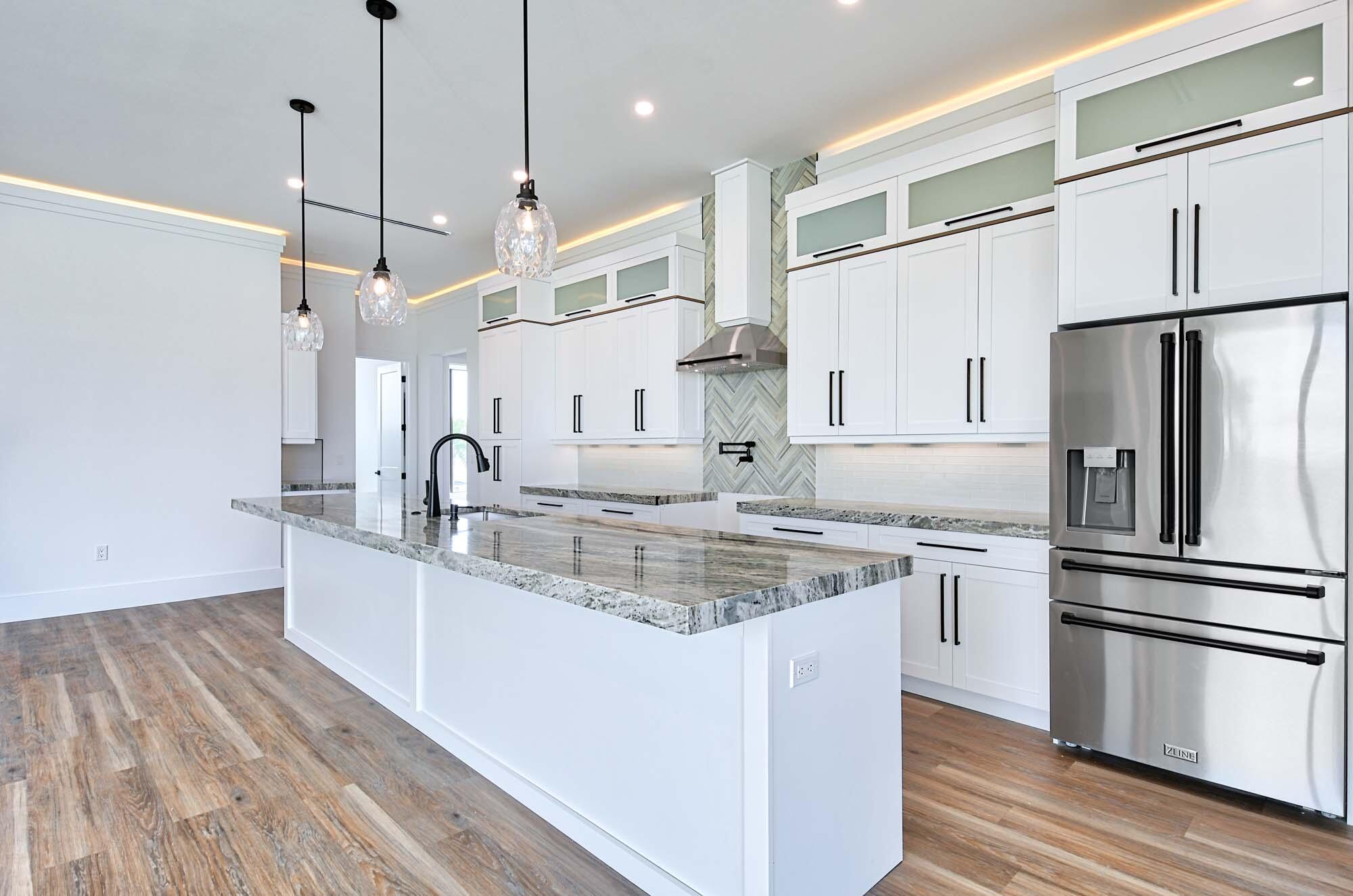 143 Trinidad Street Naples, FL 34113 - Photo 6 of 62 a kitchen with stainless steel appliances granite countertop a sink a oven a refrigerator and white cabinets with wooden floor