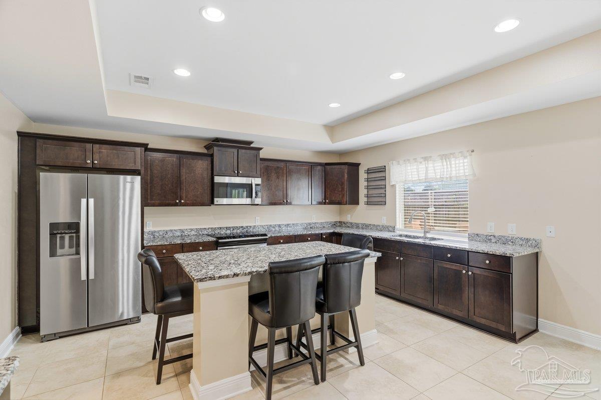 5468 Madelines Way Pace, FL 32571 - Photo 12 of 46 a kitchen with stainless steel appliances granite countertop a table and chairs in it