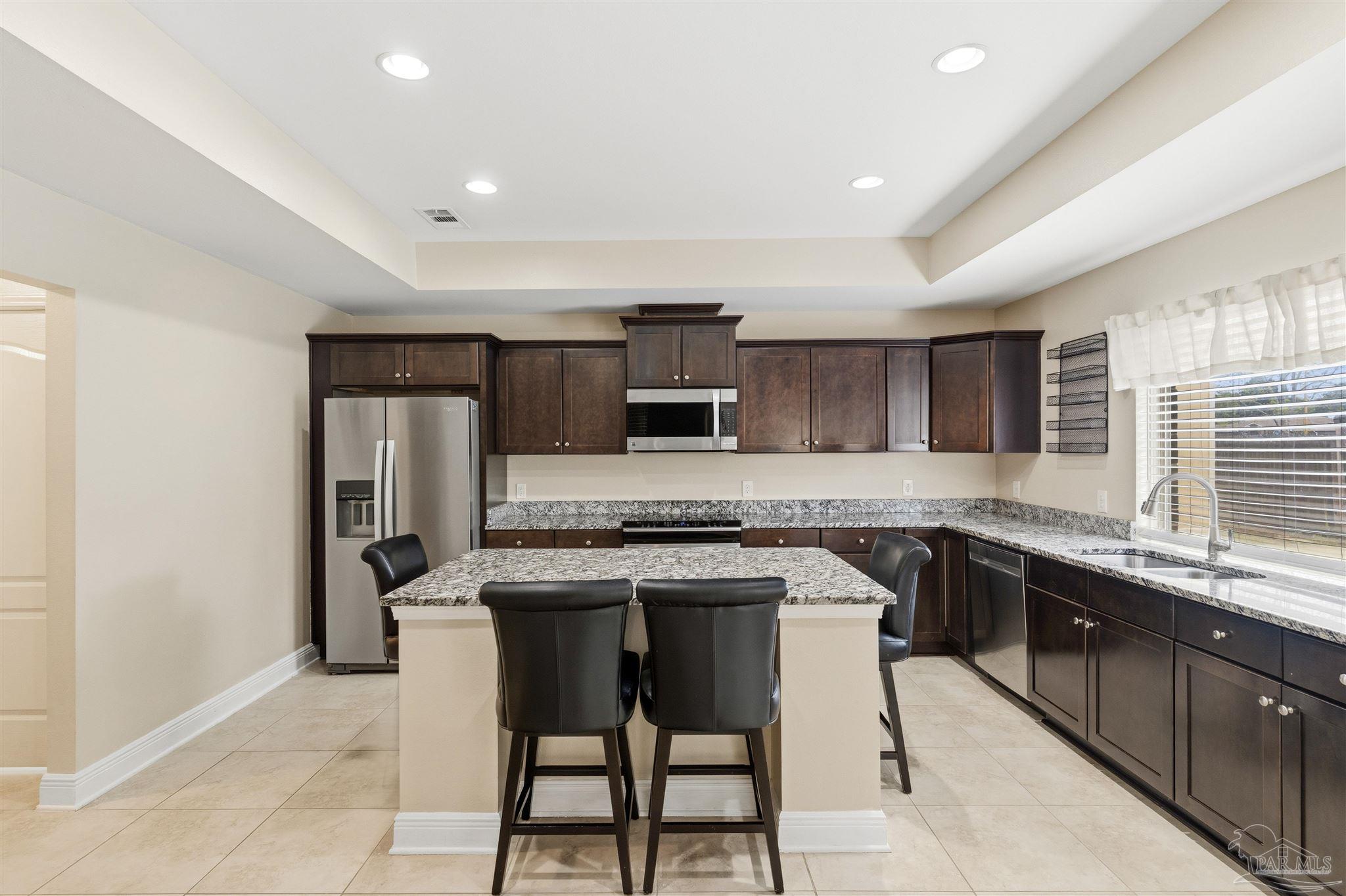 5468 Madelines Way Pace, FL 32571 - Photo 13 of 46 a kitchen with stainless steel appliances granite countertop a stove top oven a sink dishwasher and a refrigerator with wooden floor