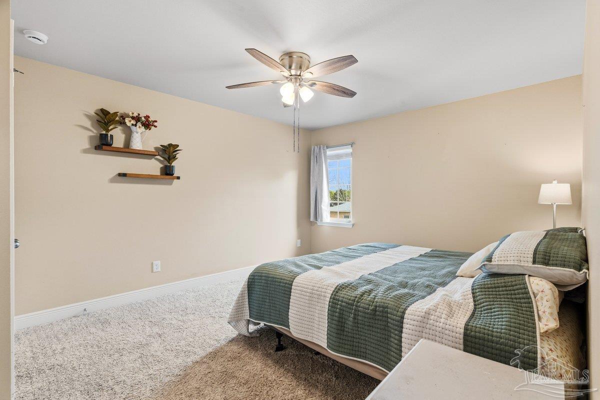 5468 Madelines Way Pace, FL 32571 - Photo 24 of 46 a bedroom with a bed and a chandelier