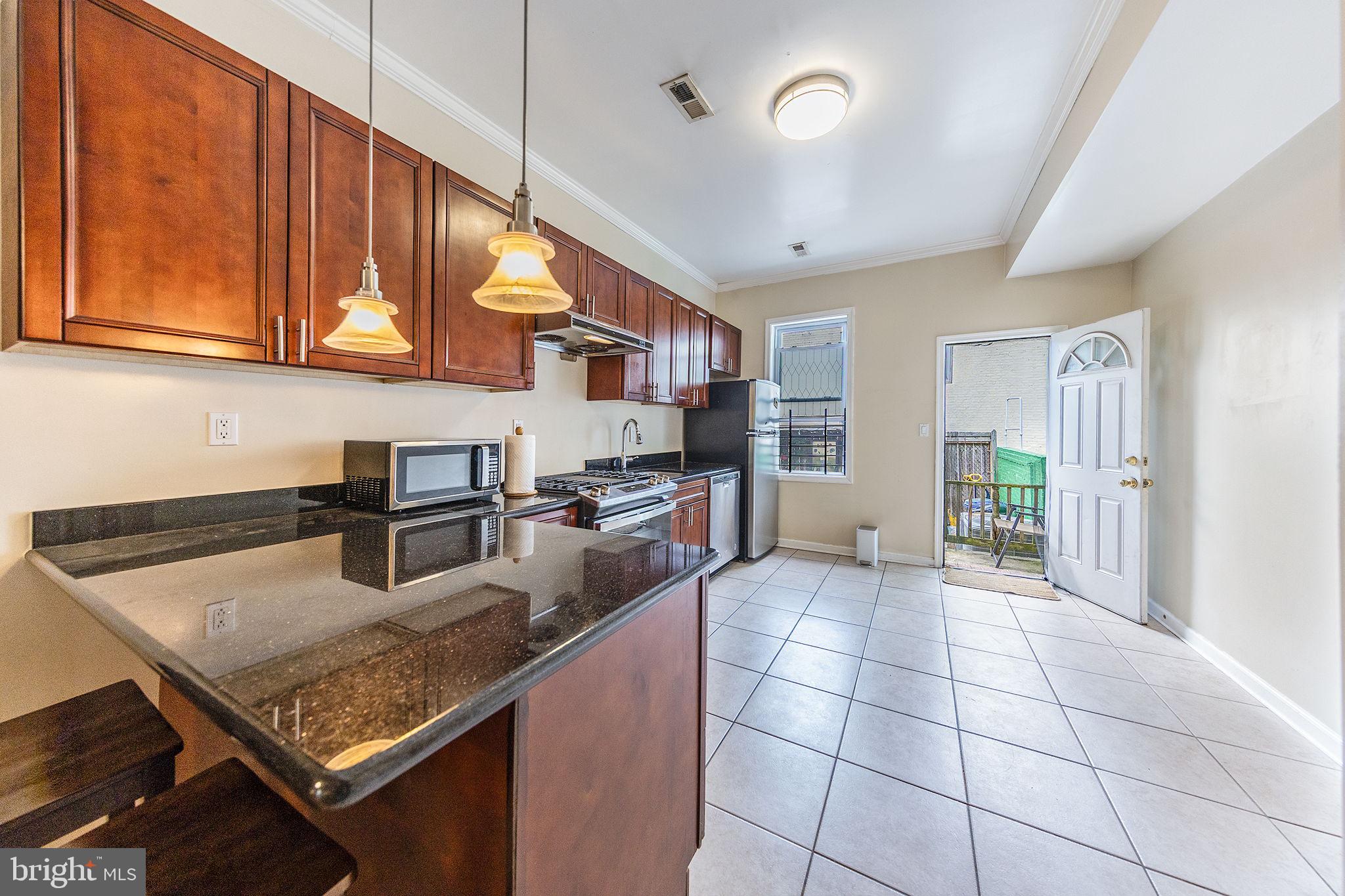 1388 Northeast E Street Northeast Washington, DC 20002 - Photo 20 of 28 a kitchen with stainless steel appliances granite countertop a stove refrigerator and cabinets