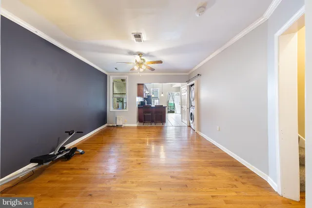 a view of empty room with wooden floor and fan
