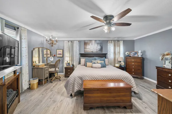 a bedroom with a bed a chandelier and flat screen tv