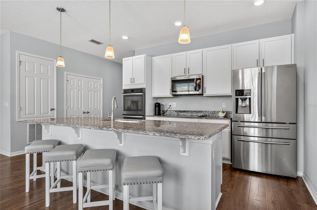 4368 Moon Shadow Loop Mulberry, FL 33860 - Photo 6 of 39 a kitchen with stainless steel appliances granite countertop a refrigerator a stove a sink a microwave and white cabinets with wooden floor