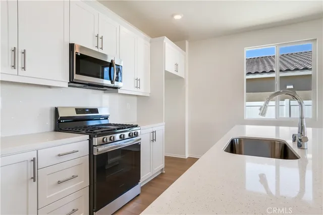 a kitchen with stainless steel appliances kitchen island a white stove top oven and sink