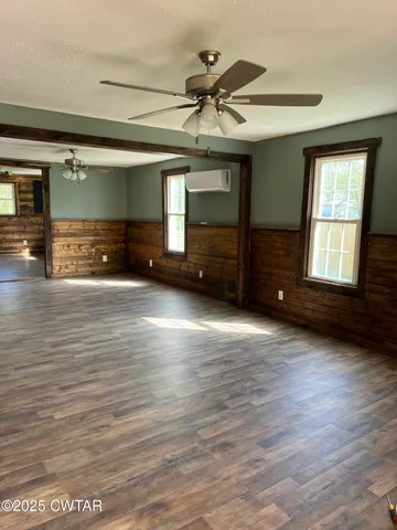 a view of an empty room with a window and wooden floor