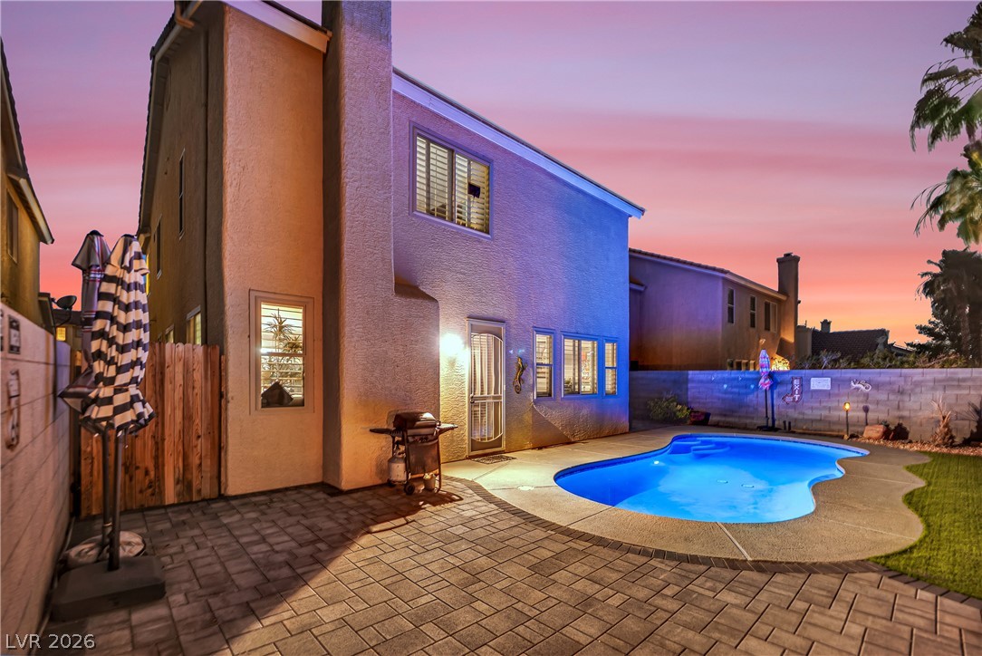 1724 Millstream Way Henderson, NV 89074 - Photo 49 of 60 A private backyard oasis with a sparkling pool awaits under a colorful evening sky.