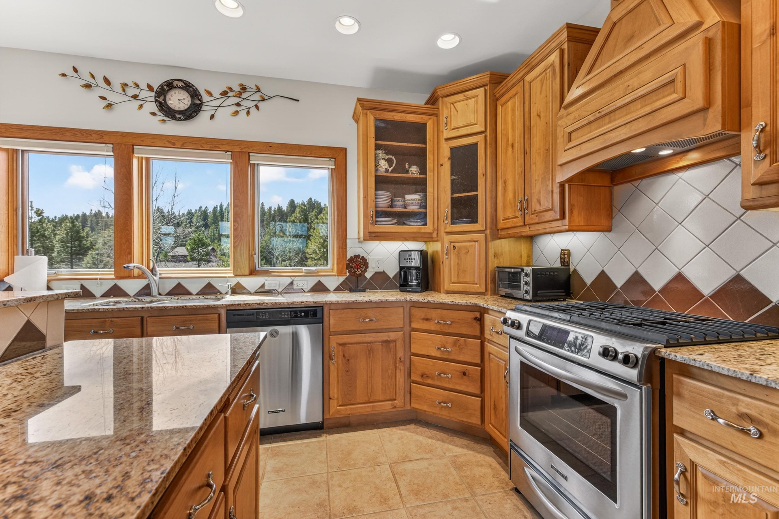 8 Bitterroot Court McCall, ID 83638 - Photo 14 of 50 Kitchen featuring stainless steel appliances, wood finish cabinetry, light stone counters, backsplash, and recessed lighting