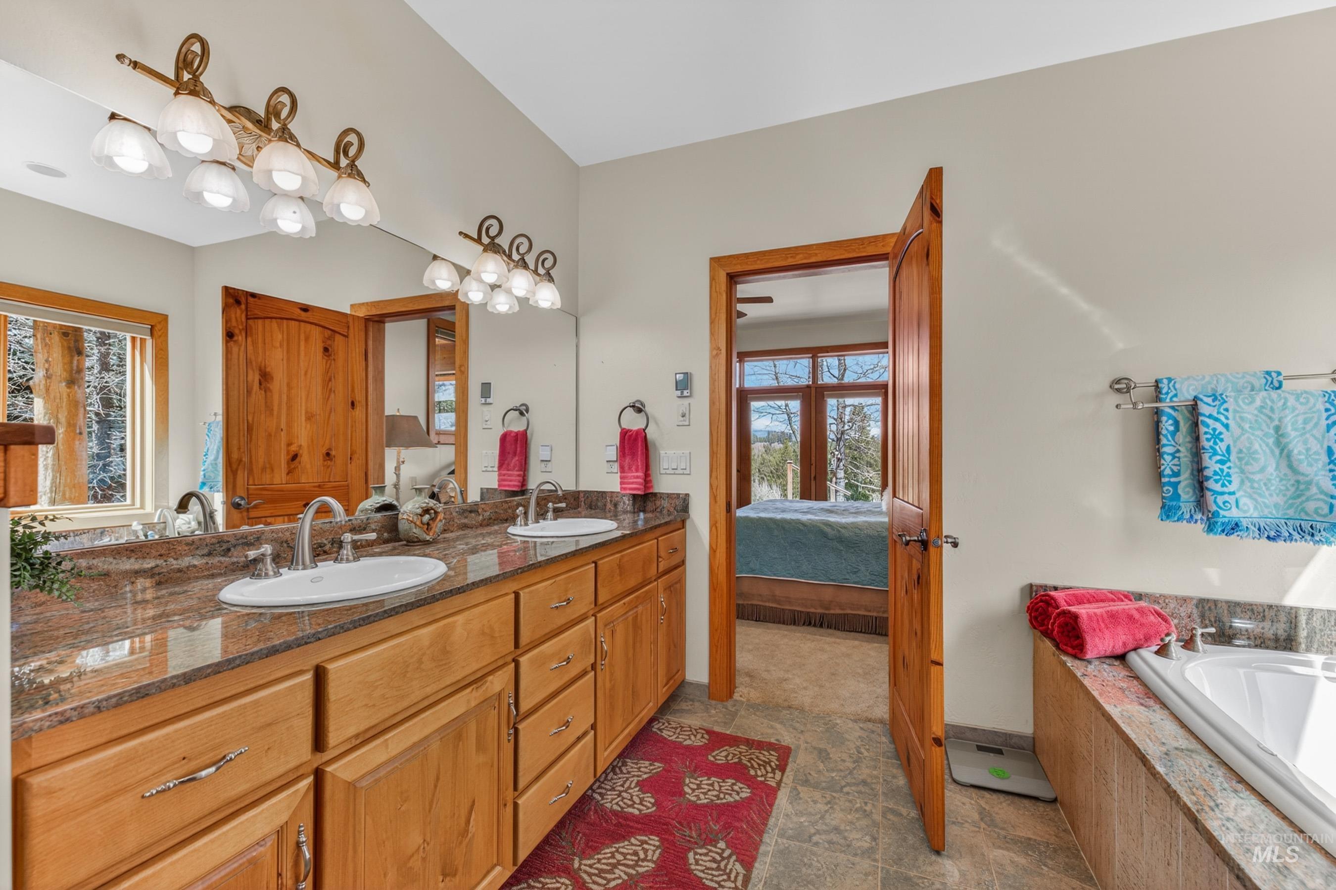 8 Bitterroot Court McCall, ID 83638 - Photo 21 of 50 Bathroom featuring double vanity, ensuite bathroom, healthy amount of natural light, and stone tile flooring