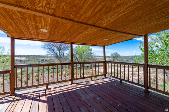 700 East Peter Springs Road Monticello, UT 84535 - Photo 38 of 57 Spacious covered wood deck with a natural wood ceiling, recessed lighting, and wood railing overlooking a natural landscape