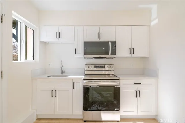 a kitchen with white cabinets stainless steel appliances and sink