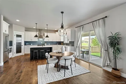 a dining room with stainless steel appliances granite countertop hardwood floor table and chairs