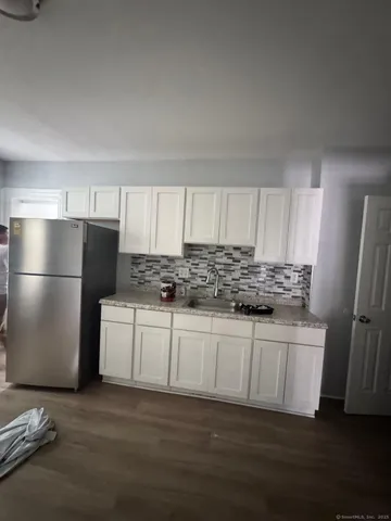 a kitchen with stainless steel appliances granite countertop a refrigerator sink and white cabinets