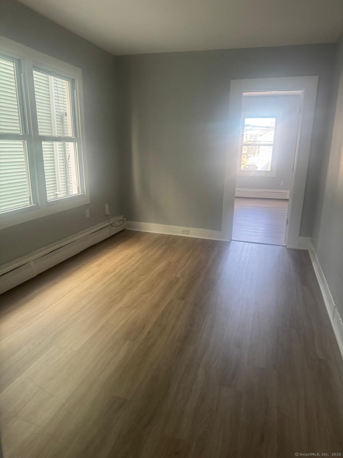 103 Caroline Street, Unit 1 Bridgeport, CT 06608 - Photo 7 of 9 an empty room with wooden floor and windows