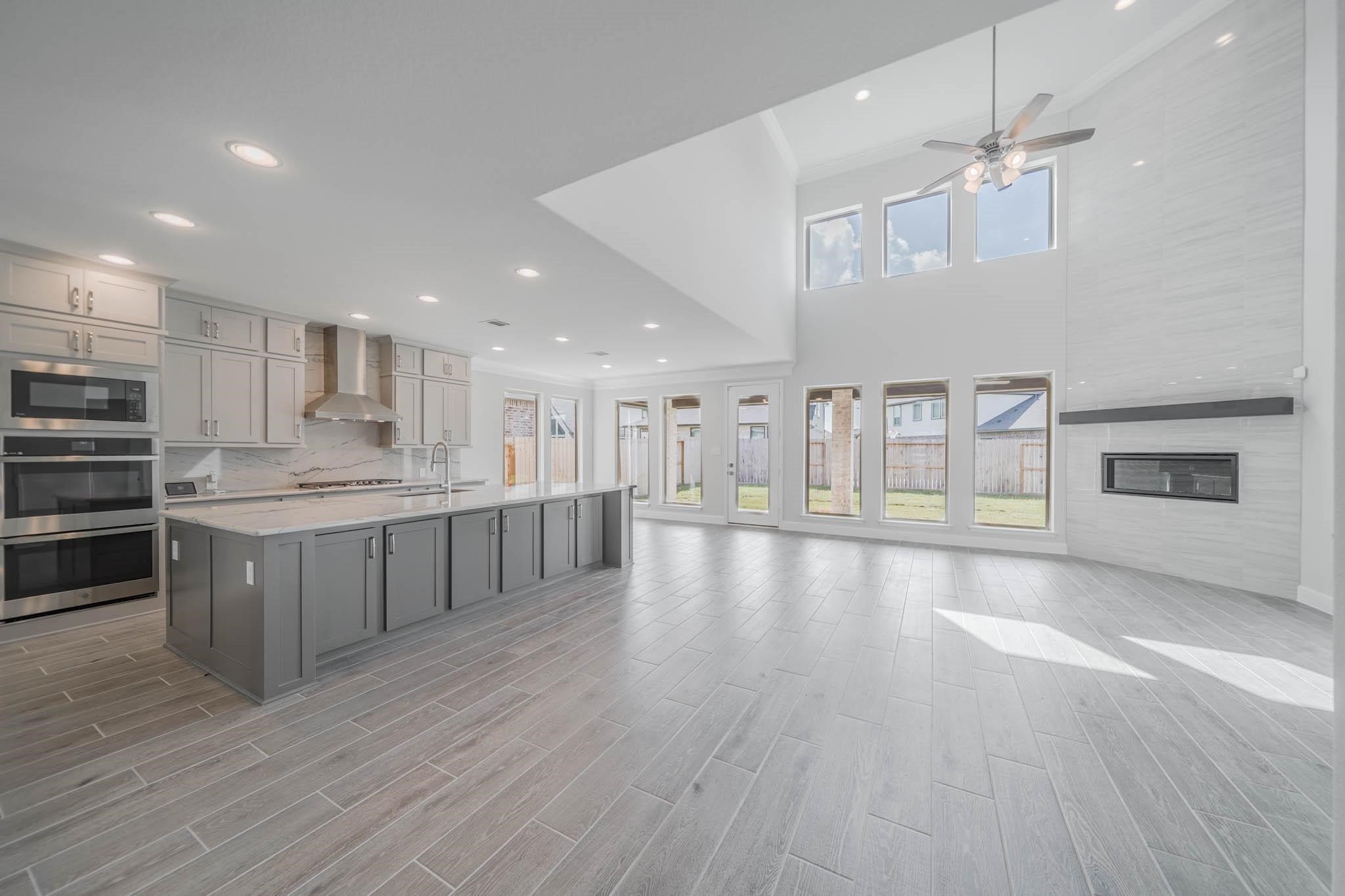 29103 Hauter Way Fulshear, TX 77441 - Photo 18 of 40 a large kitchen with kitchen island a stove a sink a refrigerator white cabinets and wooden floor