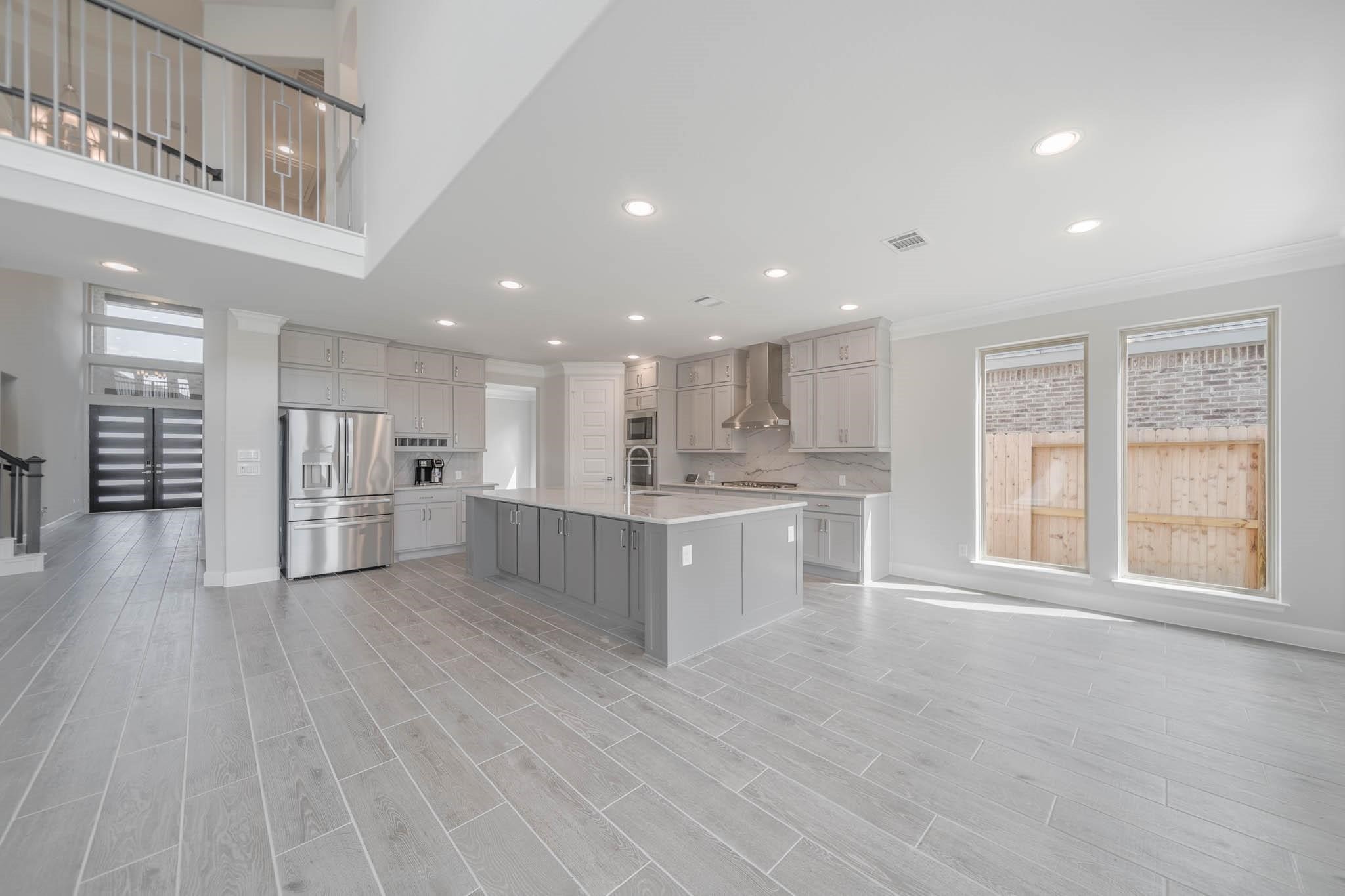 29103 Hauter Way Fulshear, TX 77441 - Photo 20 of 40 a large white kitchen with kitchen island a sink wooden floor and a large window