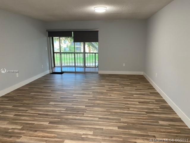 842 Southwest 9th St Circle, Unit 202 Boca Raton, FL 33486 - Photo 3 of 27 a view of an empty room with wooden floor and a window