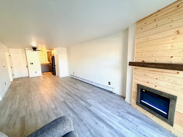 a view of empty room with wooden floor and fan