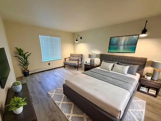 a spacious bedroom with a bed and wooden floor