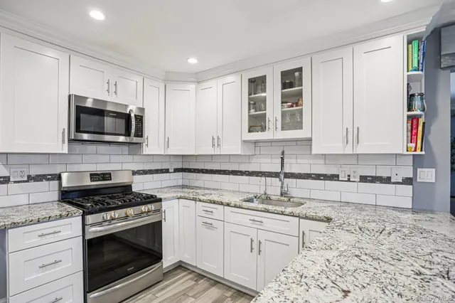 a kitchen with granite countertop a stove a sink and a microwave