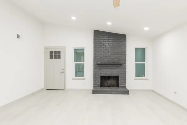 an empty room with windows and fireplace