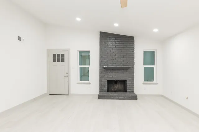 an empty room with windows and fireplace