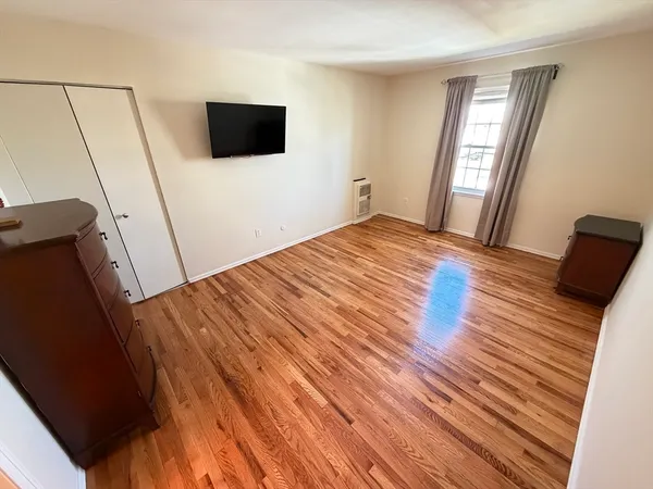 a bedroom with a bed and a flat tv screen on the dresser