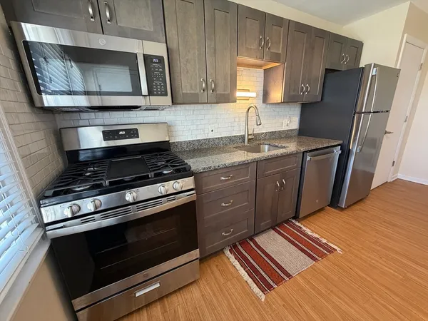 a kitchen with stainless steel appliances granite countertop a stove microwave and sink