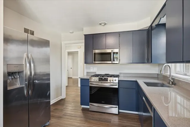 a kitchen with stainless steel appliances granite countertop a refrigerator a stove and a sink with wooden floor