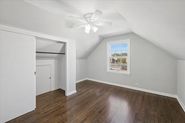 an empty room with wooden floor chandelier fan and windows