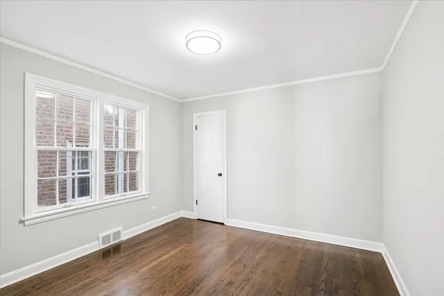 a view of an empty room with wooden floor and windows