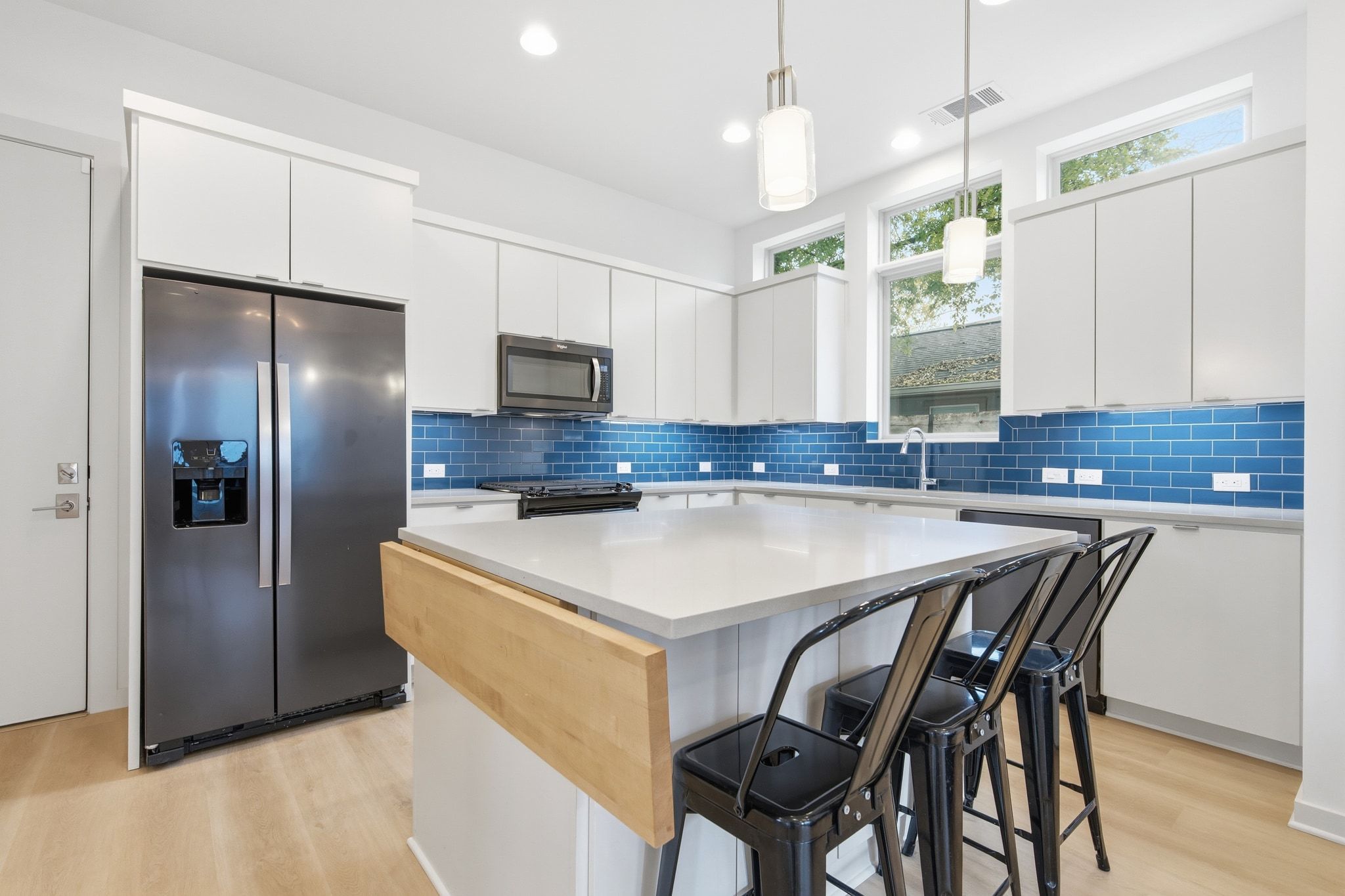 2811 Garwood Street, Unit B Austin, TX 78702 - Photo 9 of 24 Kitchen with stainless steel appliances, white cabinets, a kitchen island, a kitchen bar, and recessed lighting