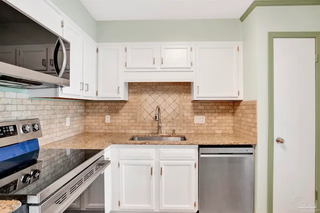 a kitchen with stainless steel appliances granite countertop a sink stove and microwave