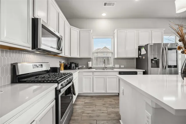 a kitchen with stainless steel appliances granite countertop a sink stove and refrigerator