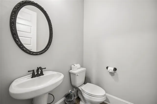 a white toilet sitting next to a white sink and a mirror