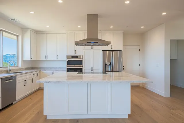 a large kitchen with stainless steel appliances granite countertop a sink a stove and a refrigerator